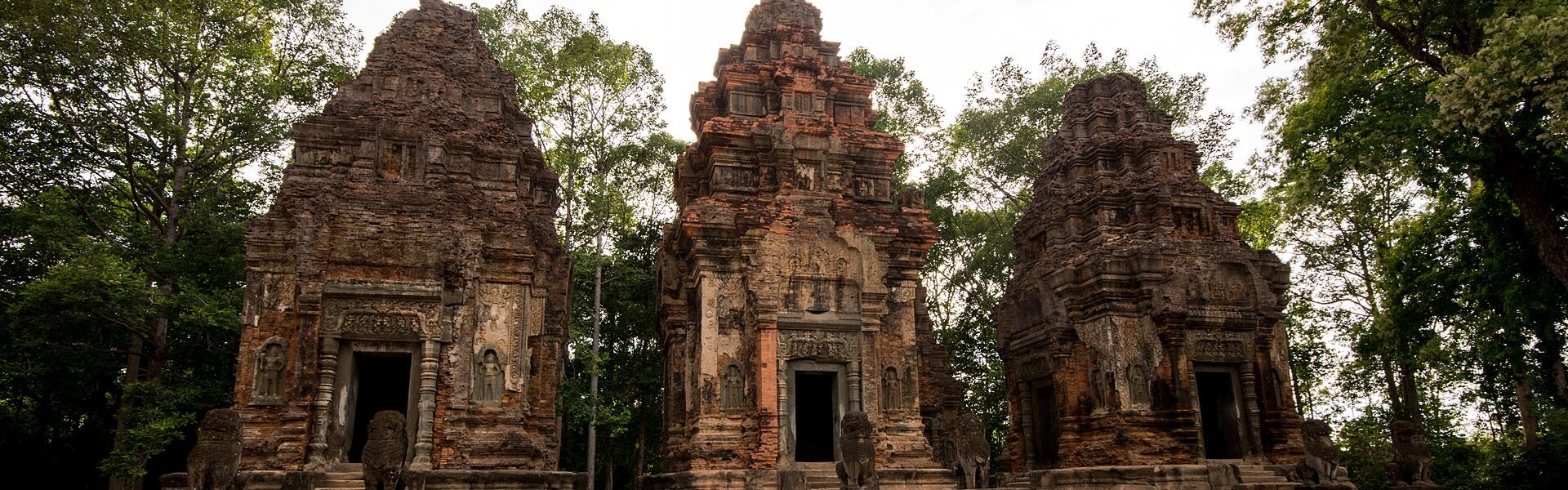 Roluos Group’s lush temple grounds in Cambodia on a Roluos Group Travel banner by Legend Travel Group.